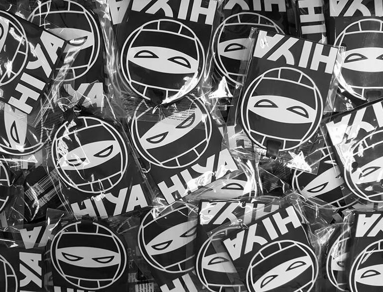 Photo of a bunch of bagged luggage tags that are the icon of volleyball combined with ninja eyes and HIYA text underneath